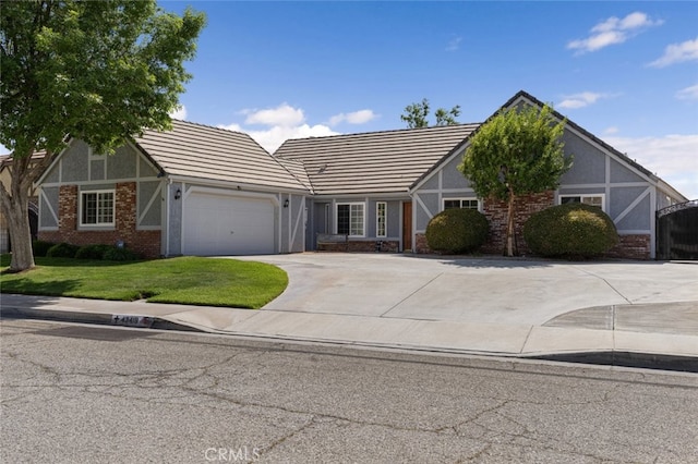 43419 37th St W, Lancaster, CA 93536 - tudor home featuring an attached garage, driveway, a front yard, stucco siding, and a tile roof