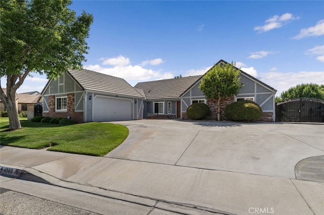 43419 37th St W, Lancaster, CA 93536 - tudor home featuring an attached garage, concrete driveway, a front lawn, and a tile roof