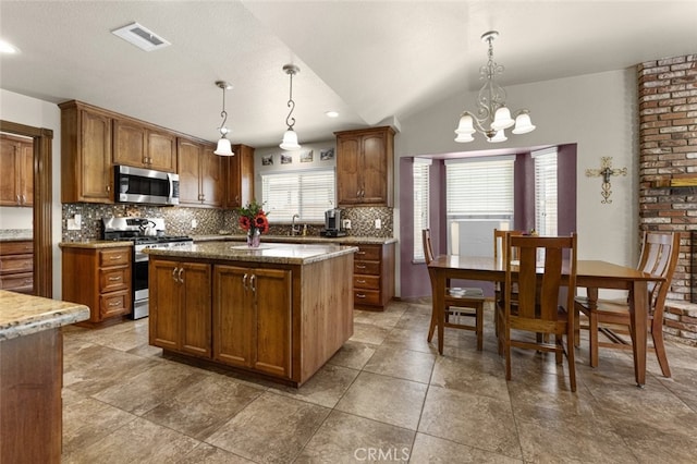 43419 37th St W, Lancaster, CA 93536 - kitchen featuring appliances with stainless steel finishes, tasteful backsplash, a chandelier, a kitchen island, and brown cabinetry