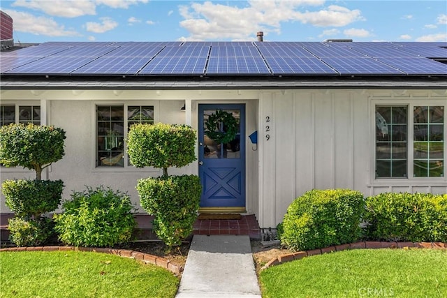 229 W Hacienda Dr, Corona, CA 92882 - property entrance featuring board and batten siding, roof mounted solar panels, and a yard