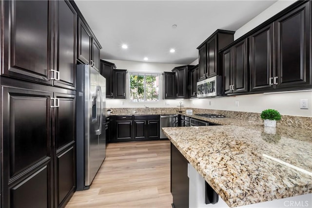 8022 Cresta Bella Rd, Rancho Cucamonga, CA 91730 - kitchen featuring stainless steel appliances, light wood-style floors, light stone countertops, recessed lighting, and dark cabinetry