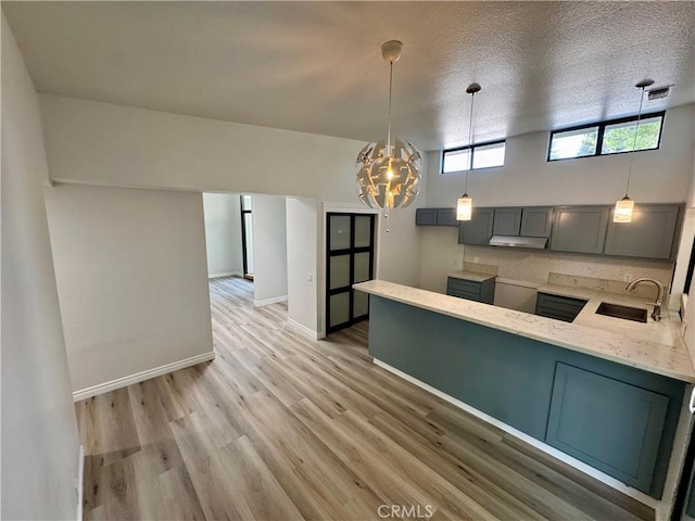 1 Paddle Ct, Sacramento, CA 95833 - kitchen featuring under cabinet range hood, light stone counters, gray cabinets, light wood-style flooring, and a peninsula