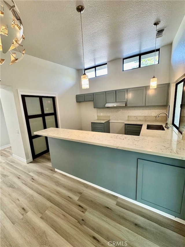 1 Paddle Ct, Sacramento, CA 95833 - kitchen featuring gray cabinetry, a textured ceiling, light stone counters, light wood-style floors, and hanging light fixtures