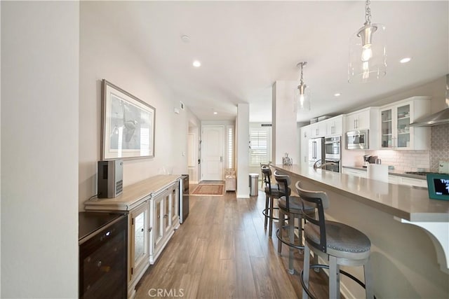 4048 Tradewinds Dr, Oxnard, CA 93035 - kitchen featuring appliances with stainless steel finishes, dark wood-type flooring, a breakfast bar area, tasteful backsplash, and white cabinets