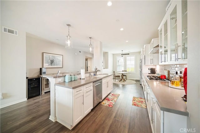 4048 Tradewinds Dr, Oxnard, CA 93035 - kitchen with appliances with stainless steel finishes, dark wood-style floors, a kitchen island with sink, white cabinets, and glass insert cabinets