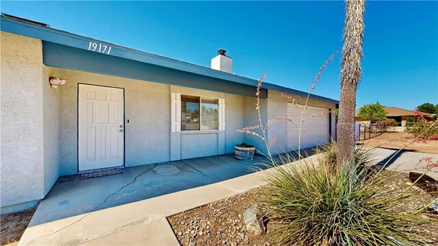 19171 Carlisle Rd, Apple Valley, CA 92307 - entrance to property featuring stucco siding, a chimney, and an attached garage