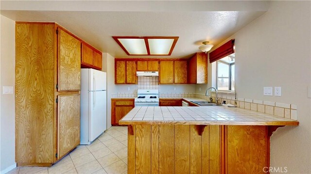 19171 Carlisle Rd, Apple Valley, CA 92307 - kitchen with white appliances, a peninsula, brown cabinetry, and tile counters