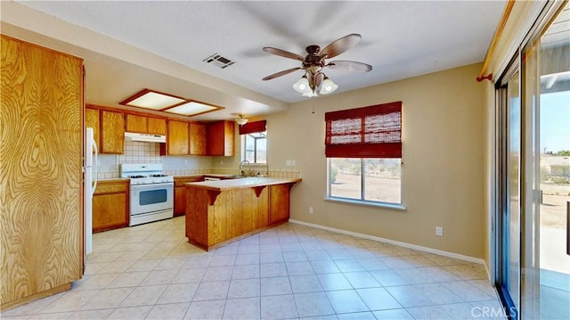 19171 Carlisle Rd, Apple Valley, CA 92307 - kitchen featuring white appliances, under cabinet range hood, a peninsula, brown cabinets, and light countertops
