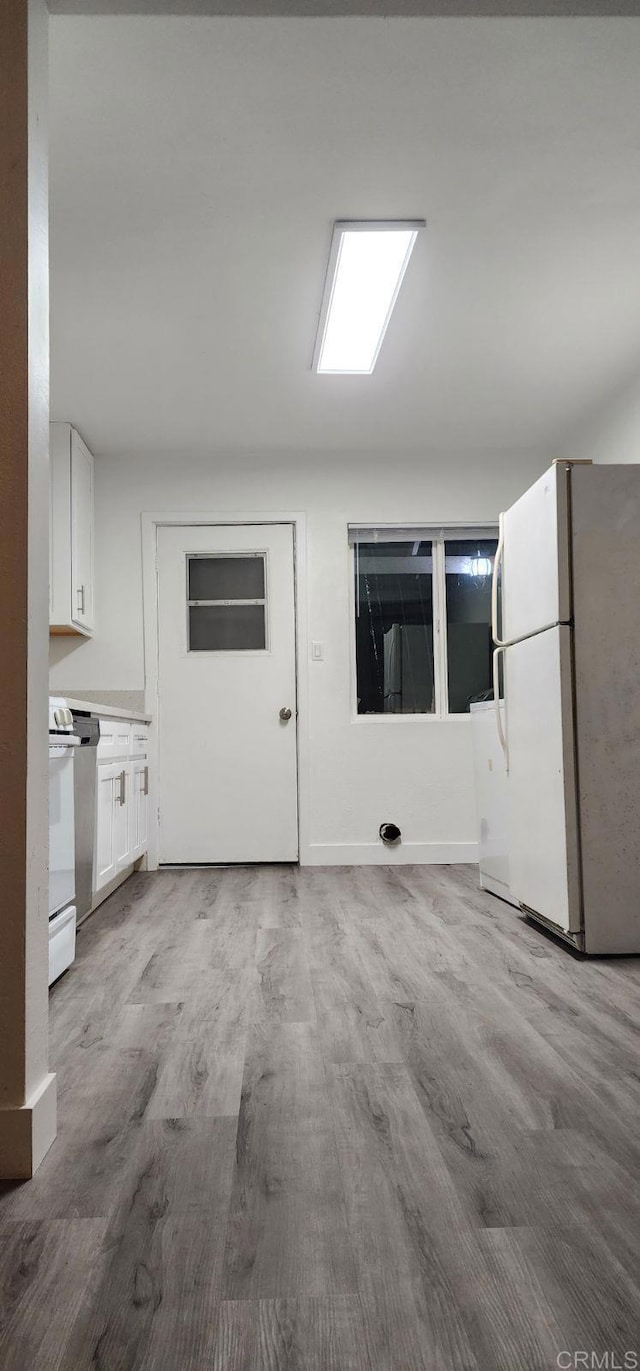 3222 42nd St, San Diego, CA 92105 - kitchen with freestanding refrigerator, range, wood finished floors, and white cabinets