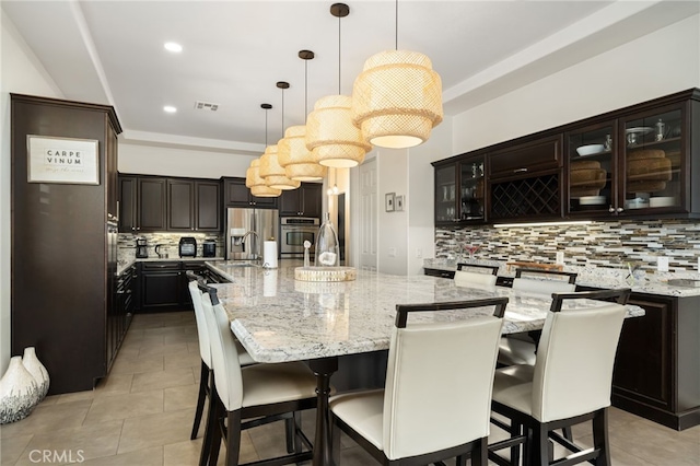 43875 Spiaggia Pl, Indio, CA 92203 - kitchen with stainless steel appliances, decorative backsplash, light stone countertops, glass insert cabinets, and recessed lighting