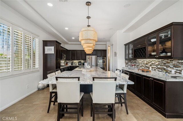 43875 Spiaggia Pl, Indio, CA 92203 - kitchen with light tile patterned floors, backsplash, appliances with stainless steel finishes, a kitchen bar, and recessed lighting