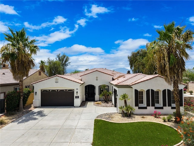 43875 Spiaggia Pl, Indio, CA 92203 - mediterranean / spanish-style home featuring a garage, stucco siding, a tiled roof, and concrete driveway