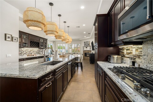 43875 Spiaggia Pl, Indio, CA 92203 - kitchen featuring stainless steel appliances, decorative backsplash, a large island with sink, glass insert cabinets, and light stone counters