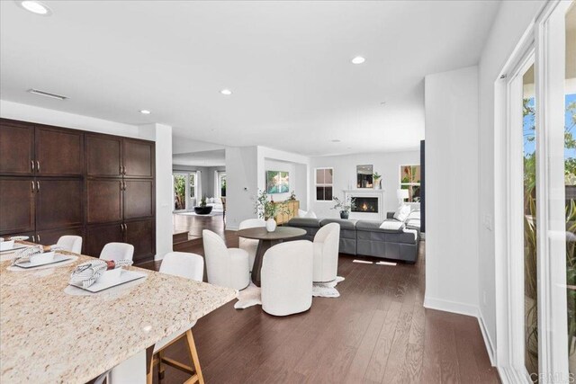 7147 Sitio Bahia, Carlsbad, CA 92009 - dining room with dark wood-style flooring, recessed lighting, and a warm lit fireplace