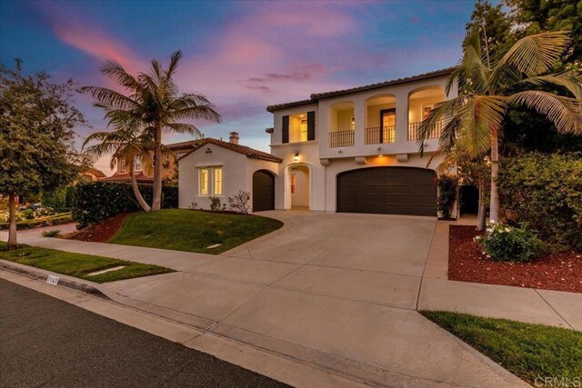 7147 Sitio Bahia, Carlsbad, CA 92009 - mediterranean / spanish house featuring a balcony, stucco siding, an attached garage, driveway, and a front yard