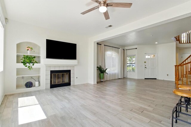 2344 Greenbriar Dr Unit A, Chula Vista, CA 91915 - unfurnished living room with stairway, a ceiling fan, built in shelves, light wood finished floors, and a tiled fireplace