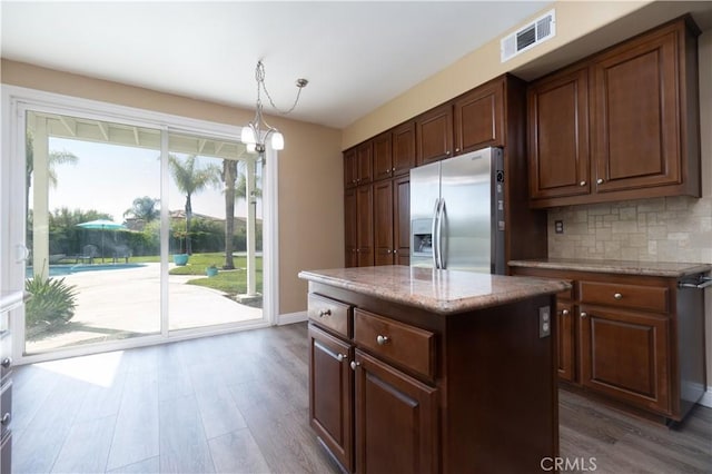 30528 Covecrest Cir, Menifee, CA 92584 - kitchen featuring stainless steel fridge, wood finished floors, decorative backsplash, hanging light fixtures, and light stone counters