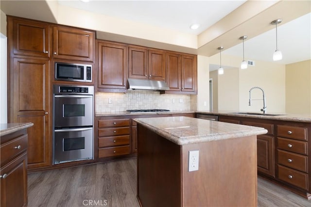 30528 Covecrest Cir, Menifee, CA 92584 - kitchen featuring appliances with stainless steel finishes, under cabinet range hood, dark wood-style flooring, light stone countertops, and recessed lighting