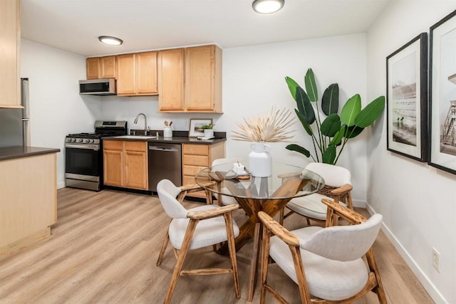13754 Mango Dr Unit 111, Del Mar, CA 92014 - kitchen featuring stainless steel appliances, dark countertops, light brown cabinets, and light wood-style floors
