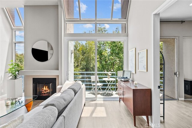 5151 Balboa Blvd Unit 303, Encino, CA 91316 - living room featuring wood finished floors, healthy amount of natural light, a glass covered fireplace, and a high ceiling