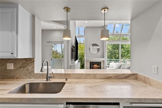 5151 Balboa Blvd Unit 303, Encino, CA 91316 - kitchen featuring stainless steel dishwasher, a lit fireplace, tasteful backsplash, decorative light fixtures, and white cabinetry