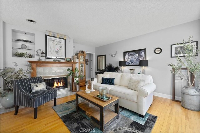 708 S Vecino Dr, Glendora, CA 91740 - living room with a textured ceiling, hardwood / wood-style floors, a tiled fireplace, and built in features