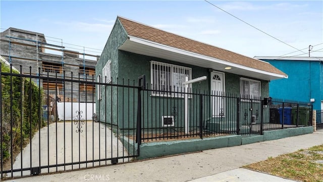 4348 Lima St, Los Angeles, CA 90011 - view of front facade with roof with shingles, a fenced front yard, and stucco siding