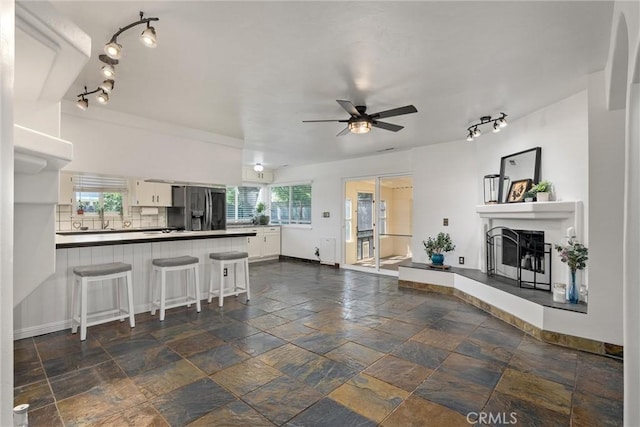 2427 Ceanothus Ave, Chico, CA 95926 - kitchen featuring rail lighting, stainless steel fridge, white cabinets, ceiling fan, and a fireplace with raised hearth