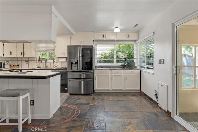 2427 Ceanothus Ave, Chico, CA 95926 - kitchen with stainless steel refrigerator with ice dispenser, stone tile floors, tasteful backsplash, white cabinets, and dishwashing machine