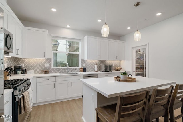 751 Winchester Dr, Oxnard, CA 93036 - kitchen featuring stainless steel appliances, a breakfast bar area, white cabinets, light countertops, and light wood finished floors