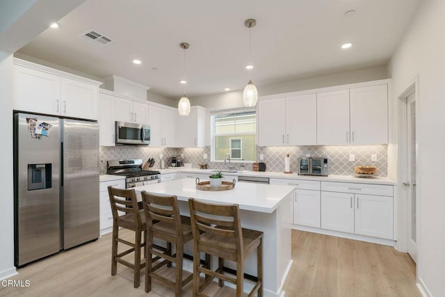 751 Winchester Dr, Oxnard, CA 93036 - kitchen with appliances with stainless steel finishes, light wood-type flooring, white cabinets, a kitchen island, and light countertops