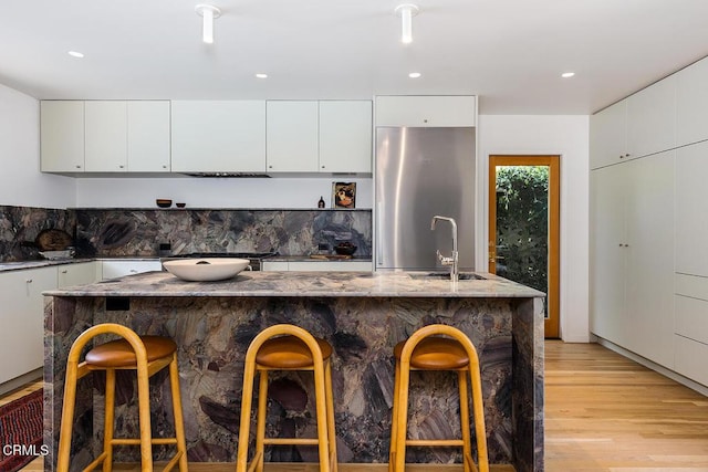 808 Inverness Dr, La Canada Flintridge, CA 91011 - kitchen with stainless steel refrigerator, light wood-style flooring, a breakfast bar area, tasteful backsplash, and light stone counters