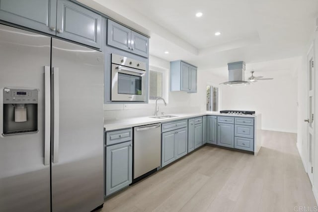 814 Hollister St Unit B, Otay Mesa, CA 92154 - kitchen featuring appliances with stainless steel finishes, island exhaust hood, light wood finished floors, a peninsula, and light countertops