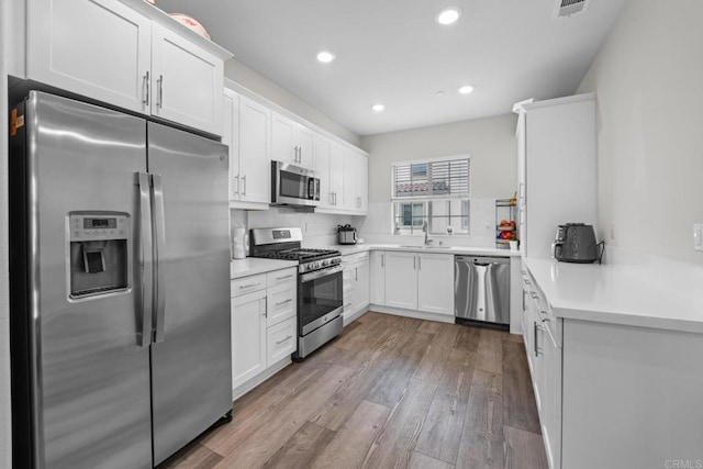 4376 Pacifica Dr Unit 2, Oceanside, CA 92056 - kitchen featuring stainless steel appliances, white cabinets, wood finished floors, recessed lighting, and light countertops