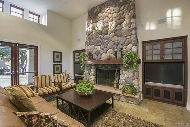 7661 Sitio Algodon, Carlsbad, CA 92009 - living room with a high ceiling, stone tile floors, french doors, and a fireplace