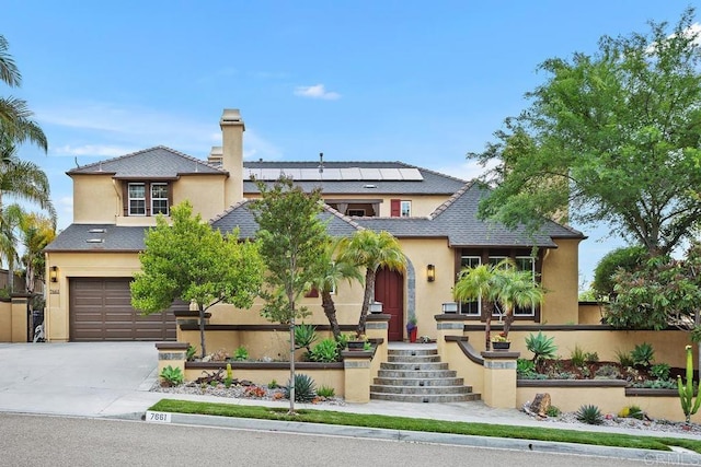 7661 Sitio Algodon, Carlsbad, CA 92009 - view of front facade with stucco siding, roof mounted solar panels, a garage, and driveway