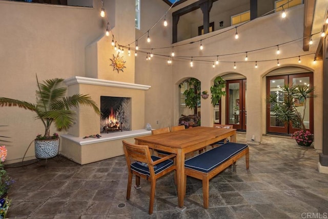 7661 Sitio Algodon, Carlsbad, CA 92009 - dining area with stone finish flooring, arched walkways, a high ceiling, and a lit fireplace