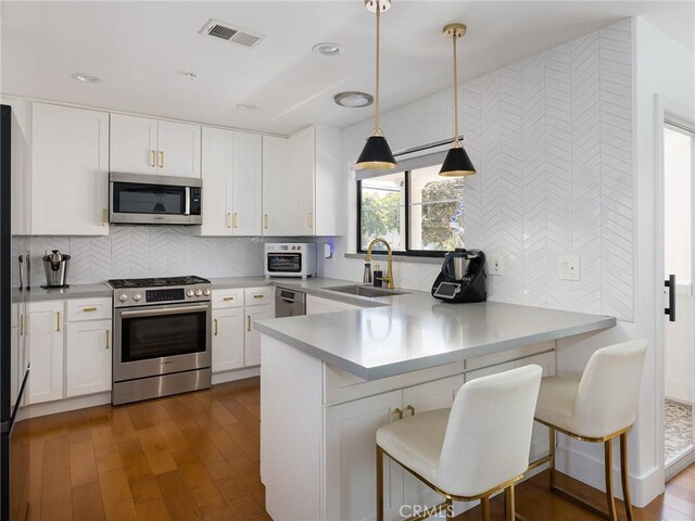 22477 Kent, Torrance, CA 90505 - kitchen featuring stainless steel appliances, a peninsula, white cabinets, hanging light fixtures, and light countertops