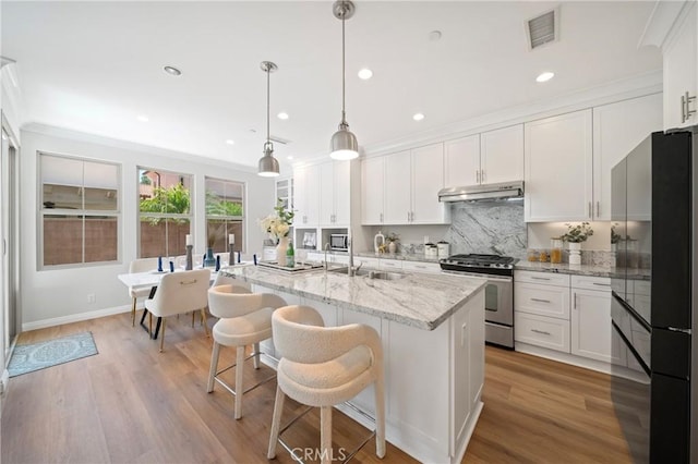 89 Overbrook, Irvine, CA 92620 - kitchen with stainless steel appliances, under cabinet range hood, white cabinetry, a kitchen island with sink, and recessed lighting