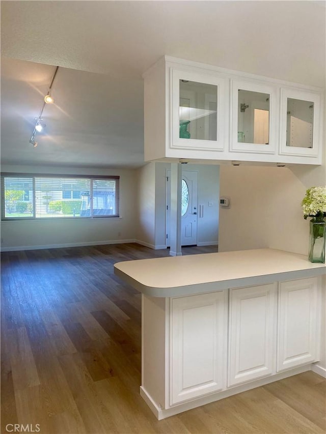 1871 Golden Rain Rd Unit M14-26H, Seal Beach, CA 90740 - kitchen with track lighting, a peninsula, light wood-type flooring, white cabinetry, and glass insert cabinets