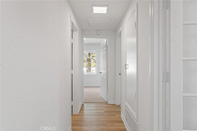 6210 Riverside Ave, Rialto, CA 92377 - hallway featuring light wood finished floors, attic access, and a textured wall
