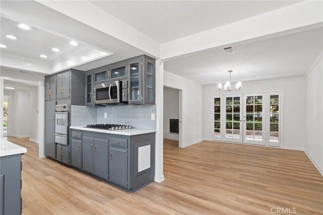 6210 Riverside Ave, Rialto, CA 92377 - kitchen with stainless steel appliances, a warming drawer, light wood-style floors, a chandelier, and tasteful backsplash