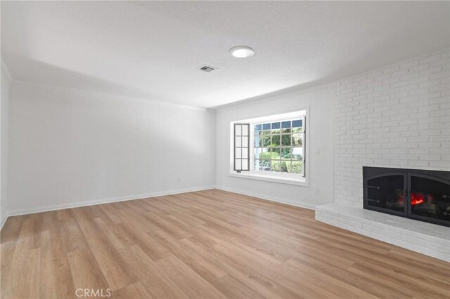 6210 Riverside Ave, Rialto, CA 92377 - unfurnished living room featuring a fireplace and light wood-style flooring