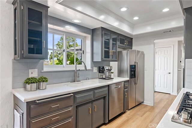 6210 Riverside Ave, Rialto, CA 92377 - kitchen with stainless steel appliances, ornamental molding, light wood-type flooring, backsplash, and light countertops