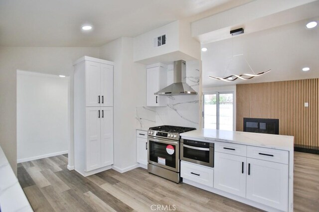 13282 Cherry St, Westminster, CA 92683 - kitchen featuring wall chimney exhaust hood, gas range, a peninsula, white cabinets, and light wood-style flooring