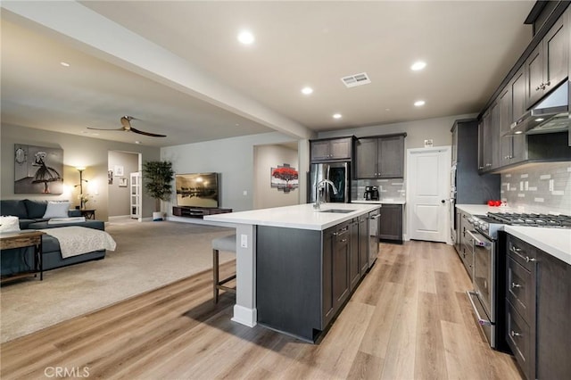 24420 Crooked Trail Dr, Menifee, CA 92584 - kitchen with under cabinet range hood, open floor plan, appliances with stainless steel finishes, light countertops, and recessed lighting