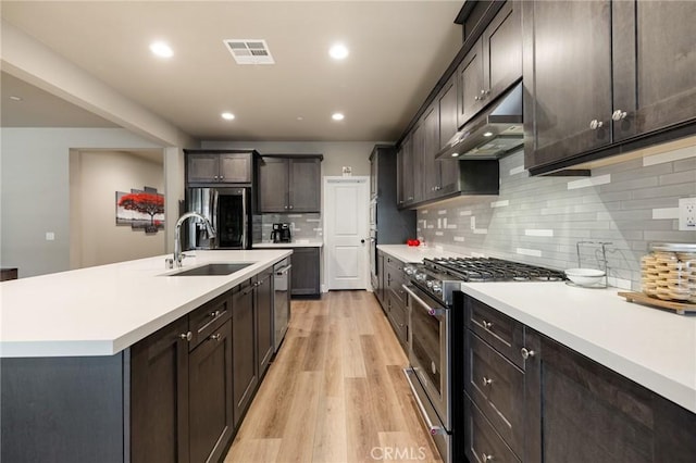 24420 Crooked Trail Dr, Menifee, CA 92584 - kitchen featuring stainless steel appliances, under cabinet range hood, light wood-style floors, light countertops, and decorative backsplash