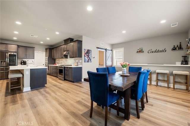 24420 Crooked Trail Dr, Menifee, CA 92584 - dining area featuring a barn door, light wood-style flooring, and recessed lighting