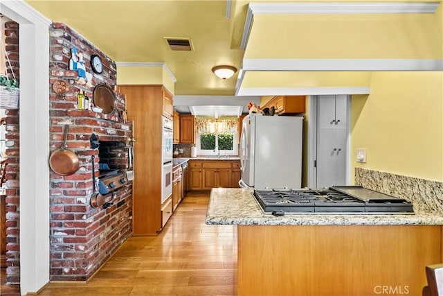 9214 Mclennan Ave, Northridge, CA 91343 - kitchen with white appliances, brown cabinetry, light wood finished floors, light stone counters, and a peninsula