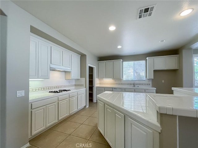 41926 Bonita Dr, Palmdale, CA 93551 - kitchen featuring tile countertops, under cabinet range hood, decorative backsplash, white gas cooktop, and recessed lighting